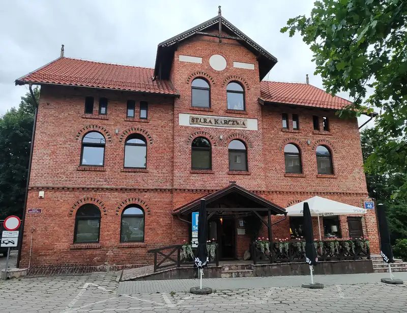 Budynek Starej Karczmy z czerwonej cegły z zadaszonym wejściem